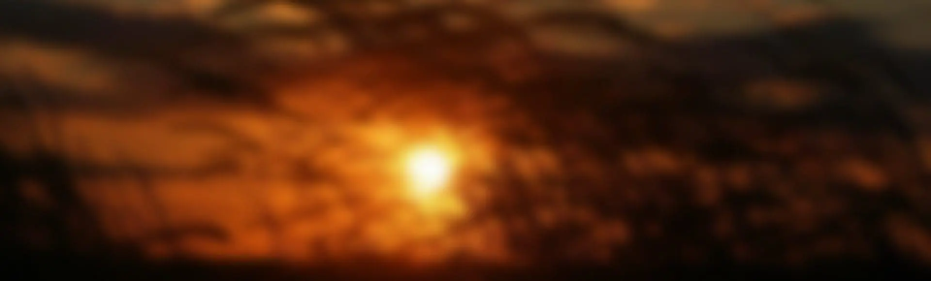 A blurry image of the sun setting in the sky.